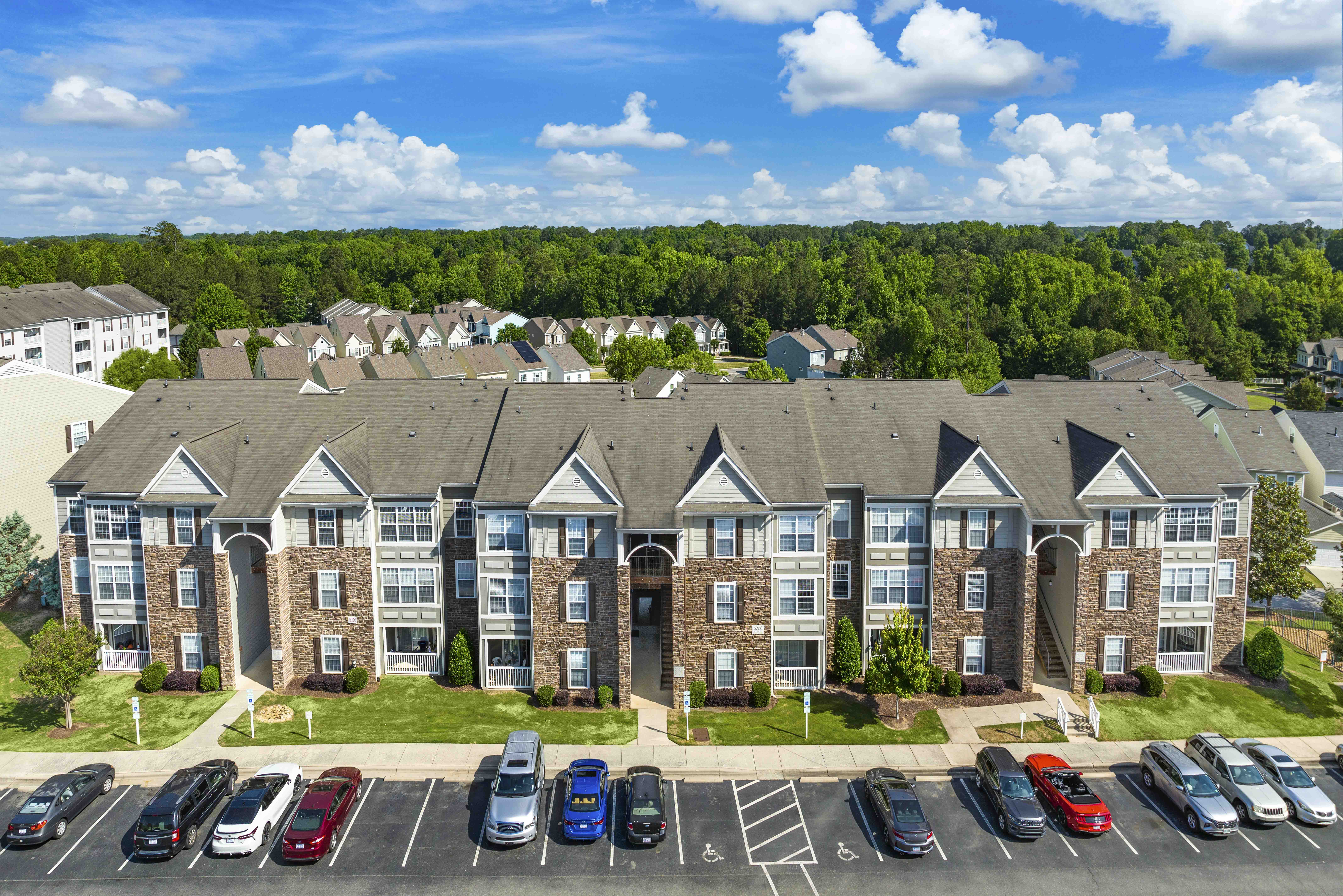 an aerial view of an apartment building with parking lot and cars