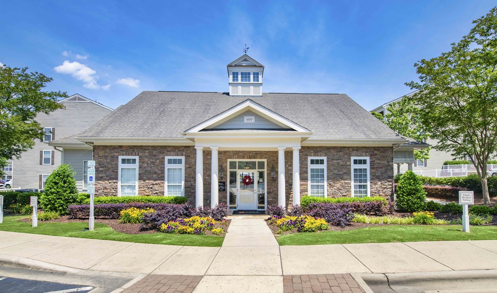 the front of a brick house with white pillars and a porch