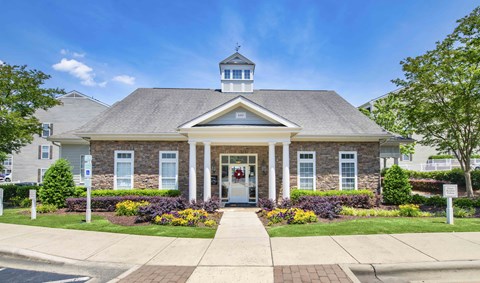 the front of a brick house with white pillars and a porch