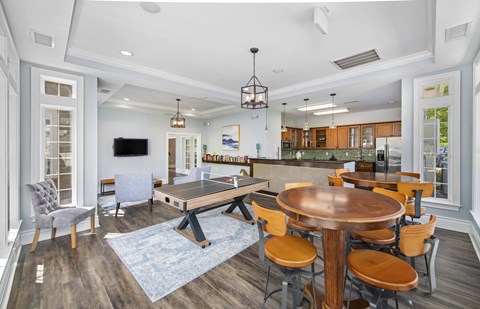 a living room with a ping pong table and a kitchen