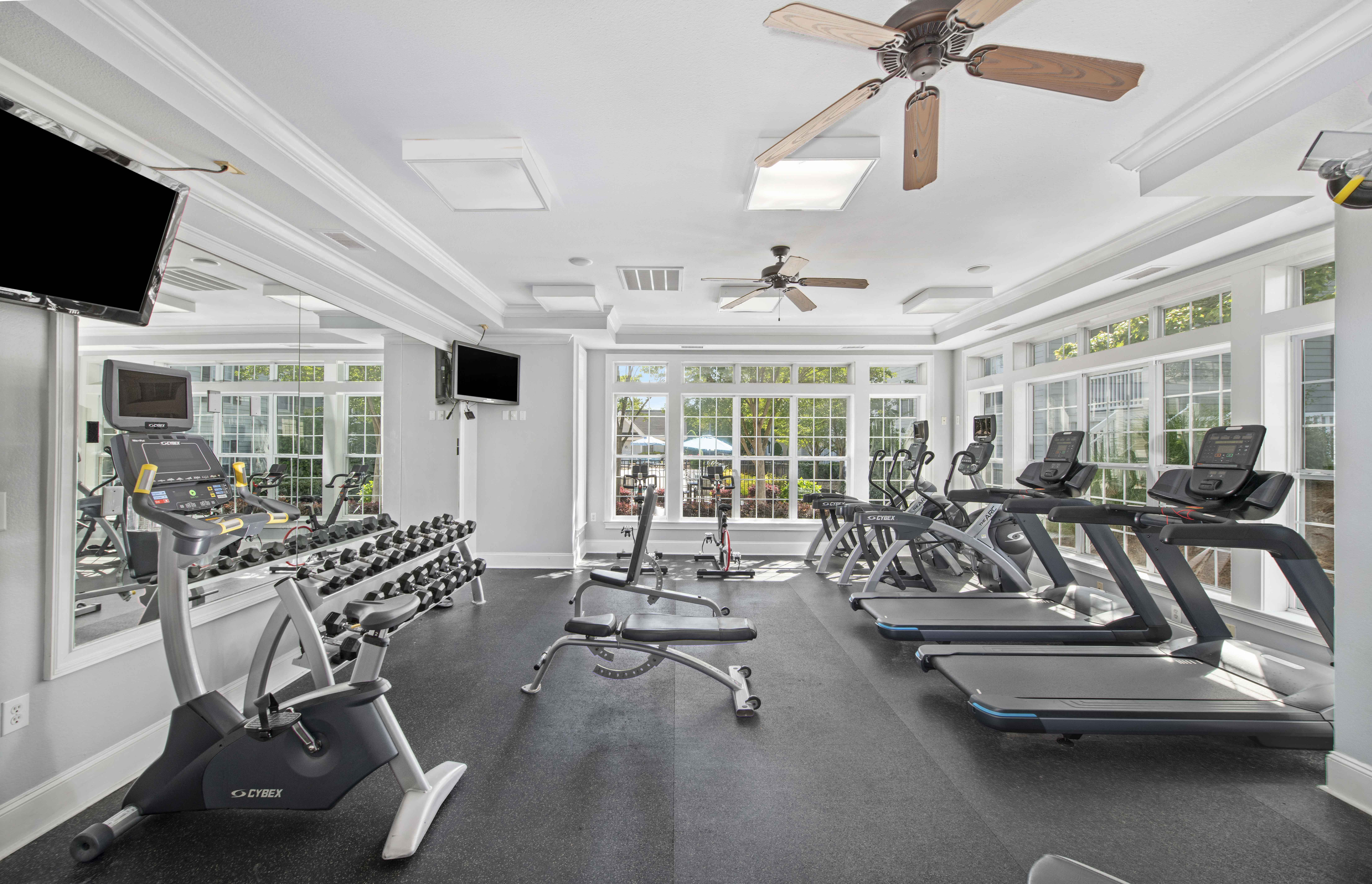 a gym with rows of exercise equipment and windows