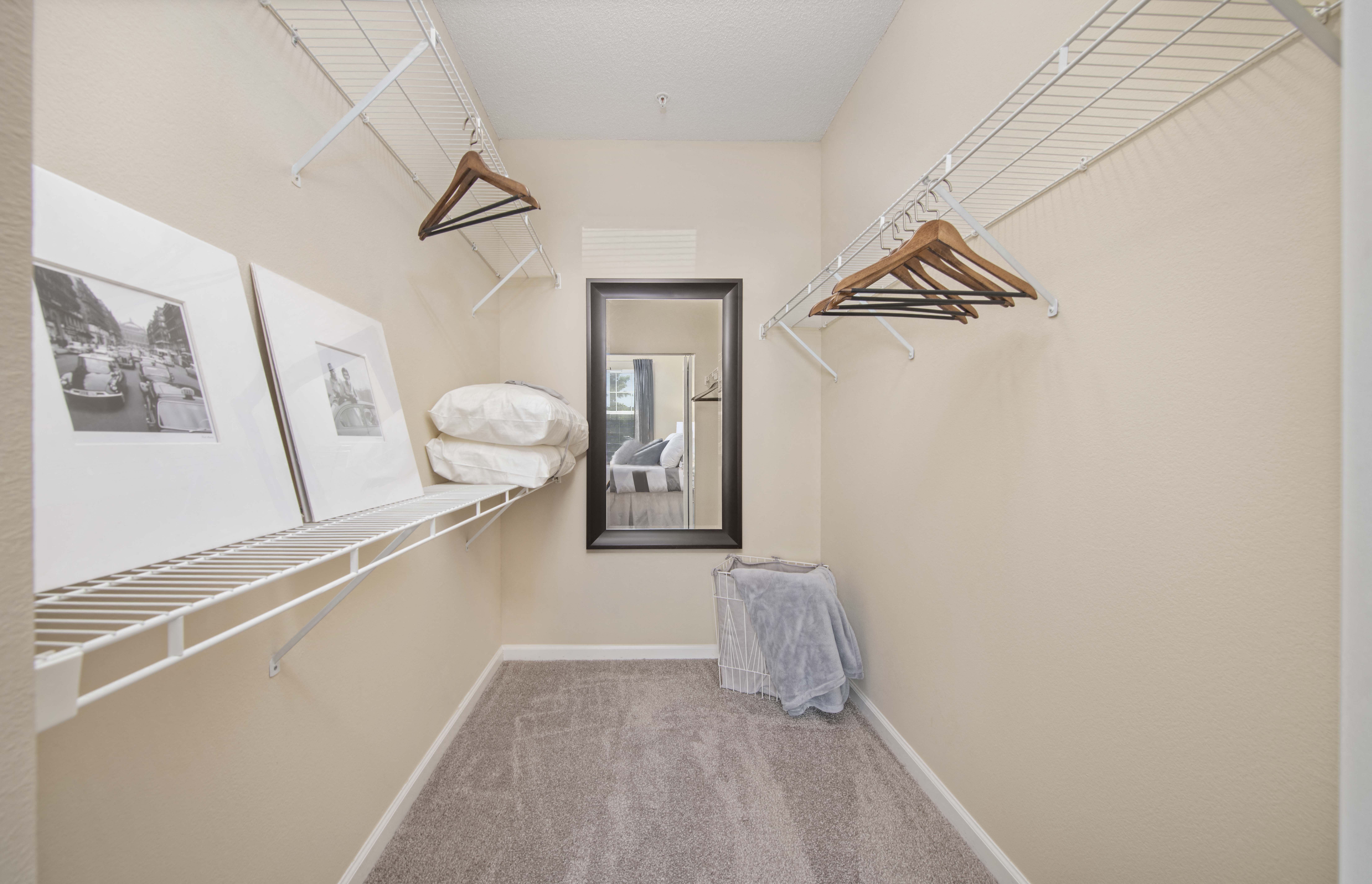 a walk in closet with two hanging racks and a mirror
