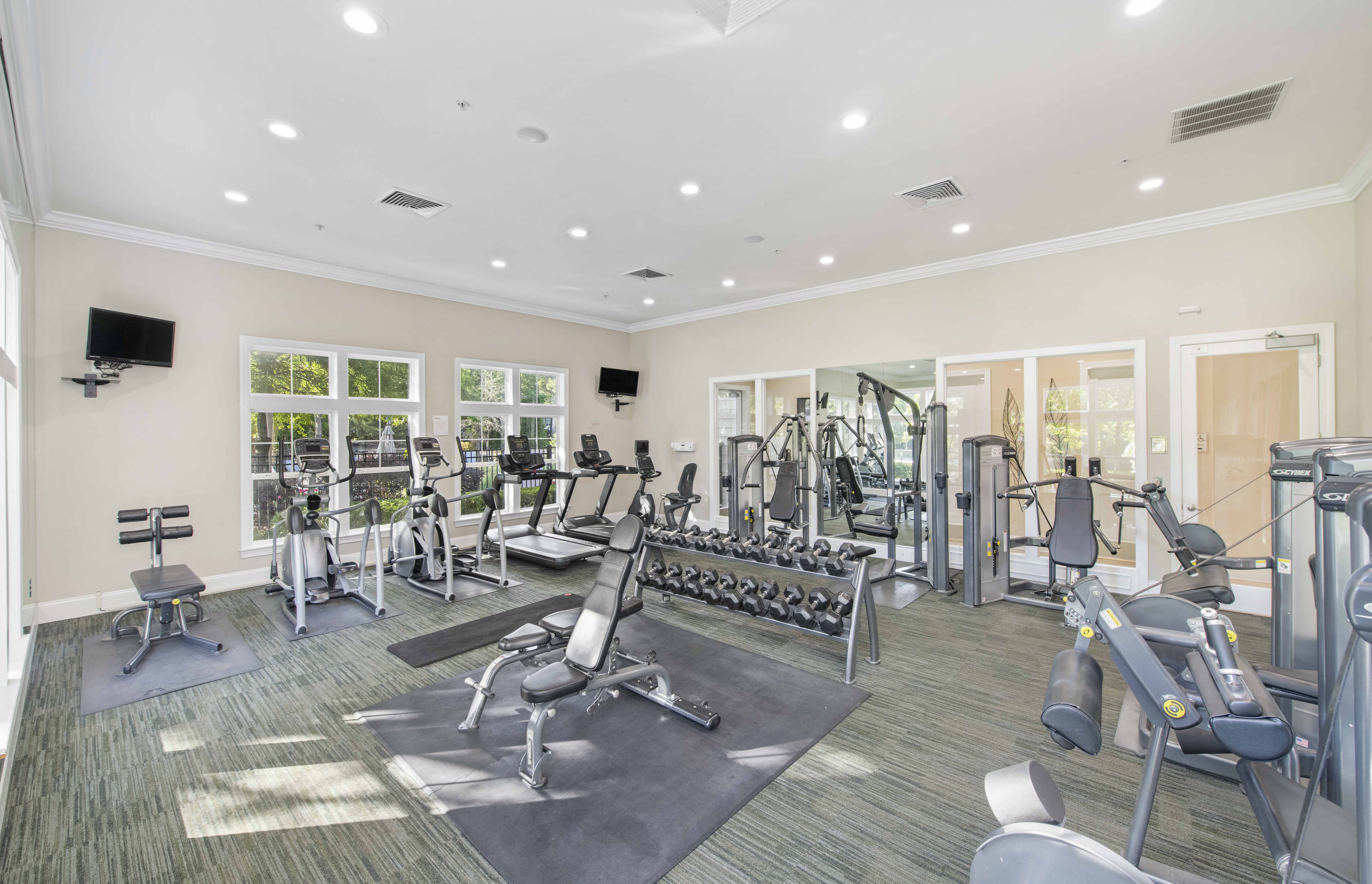 a gym with weights and cardio equipment and windows