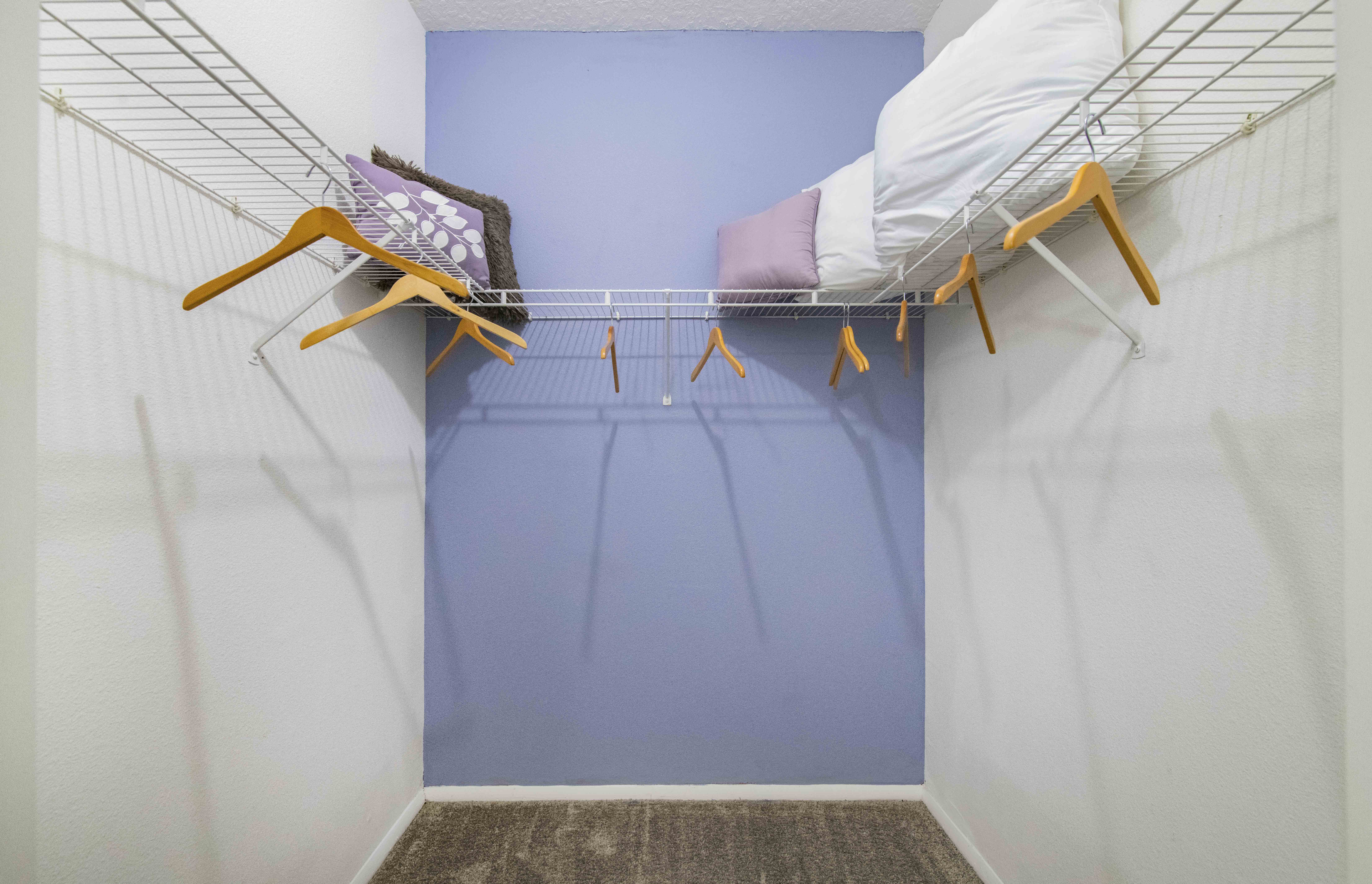 a bedroom with a bed in a closet with a rack on the wall