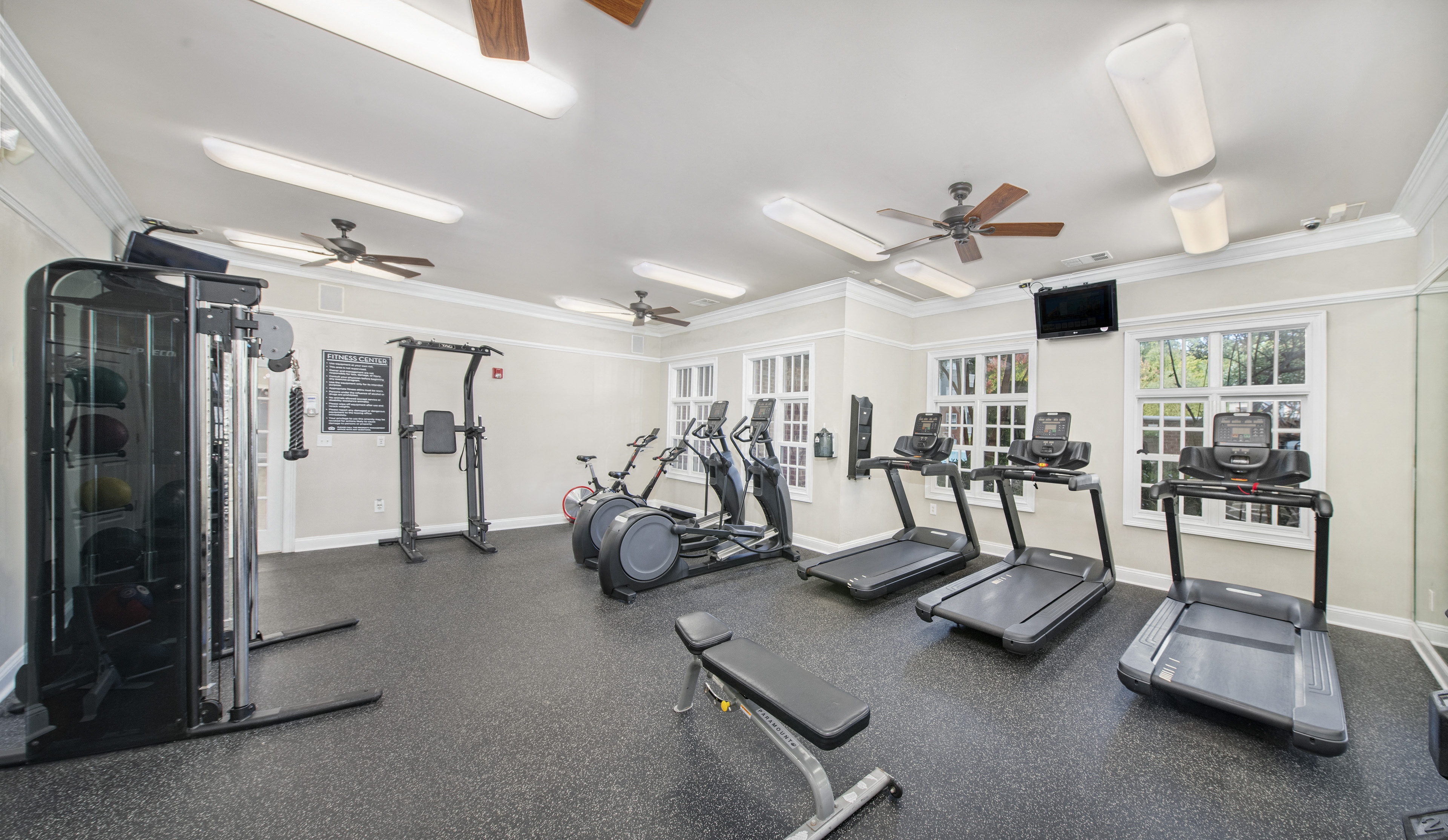 a gym with cardio machines and weights on the floor and windows