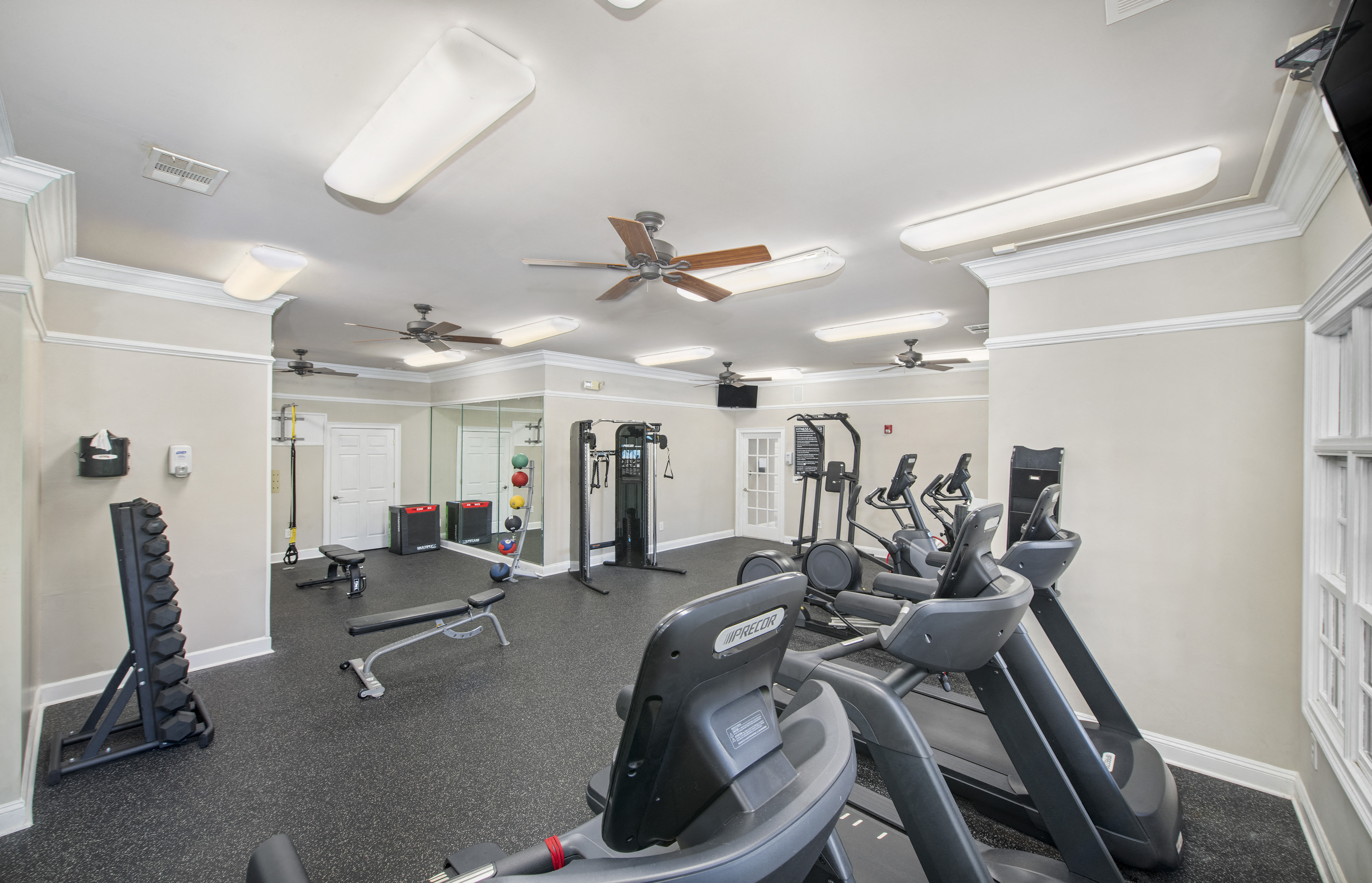 a gym with various exercise machines and ceiling fans