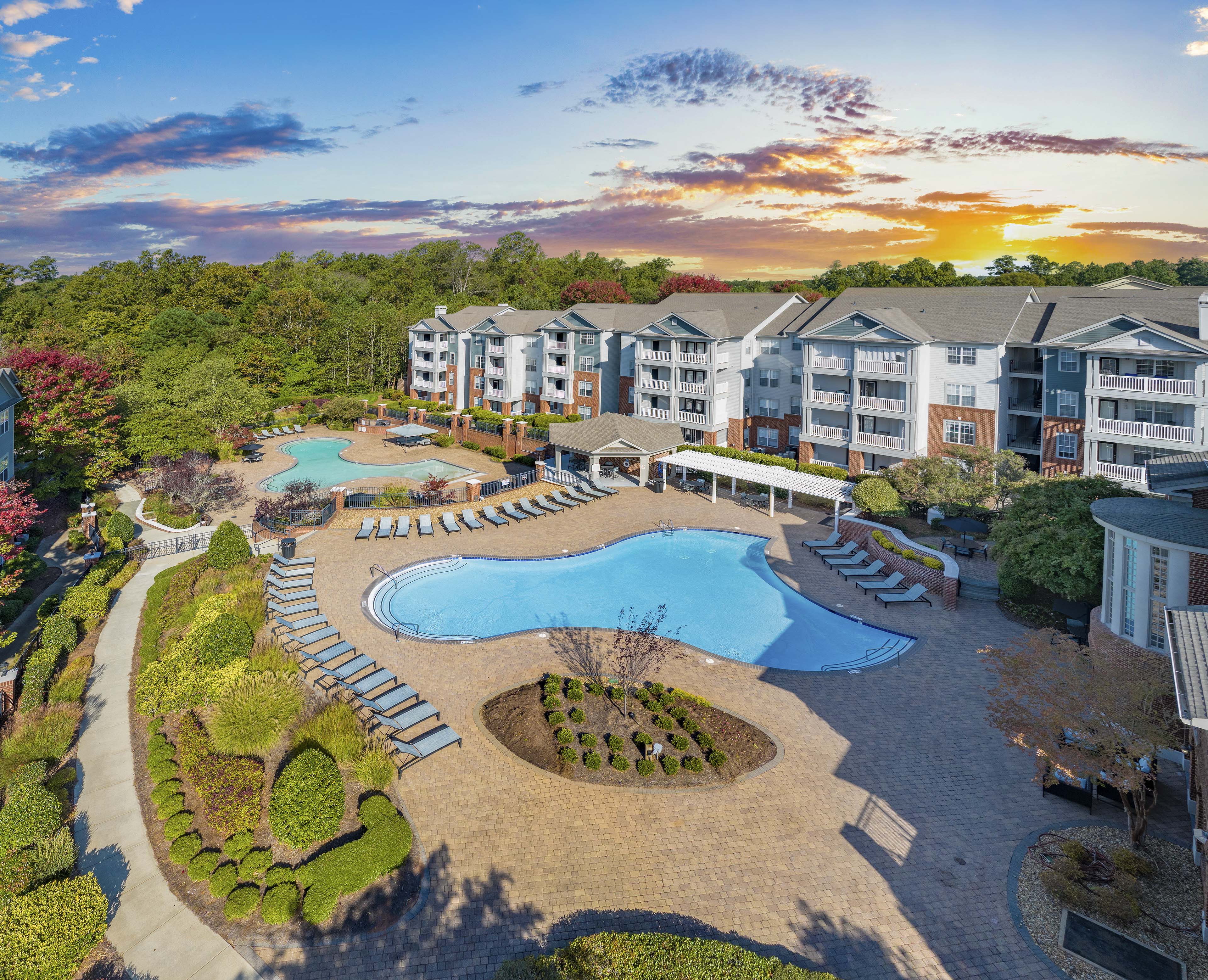 an aerial view of an outdoor pool and resort building with trees
