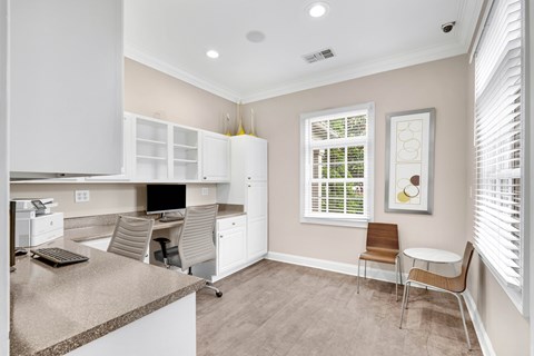 A kitchen area with a desk and chairs.