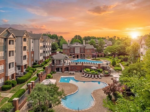 A sunset view of a pool and apartment complex.