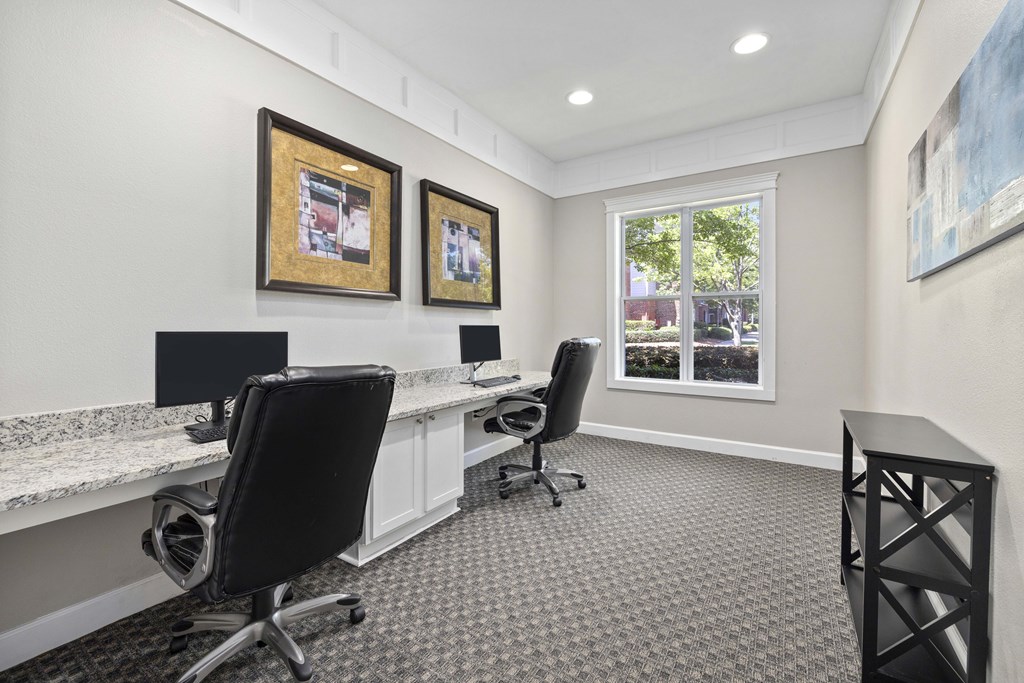 A room with two chairs and two desks with computers.