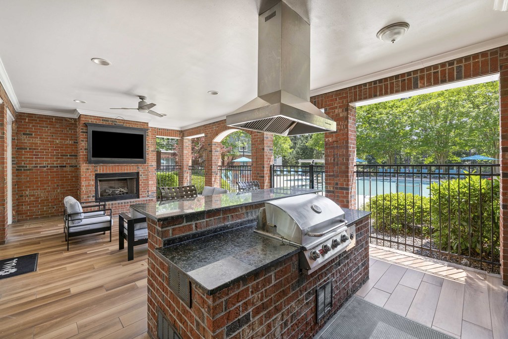A modern outdoor kitchen with a grill and a television.
