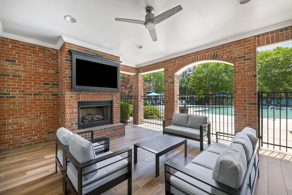 A patio with a brick fireplace and a television above it.