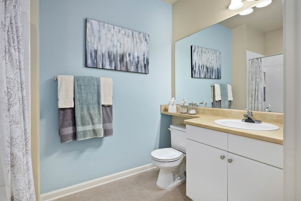 A bathroom with a toilet, sink, and two towels hanging on the wall.