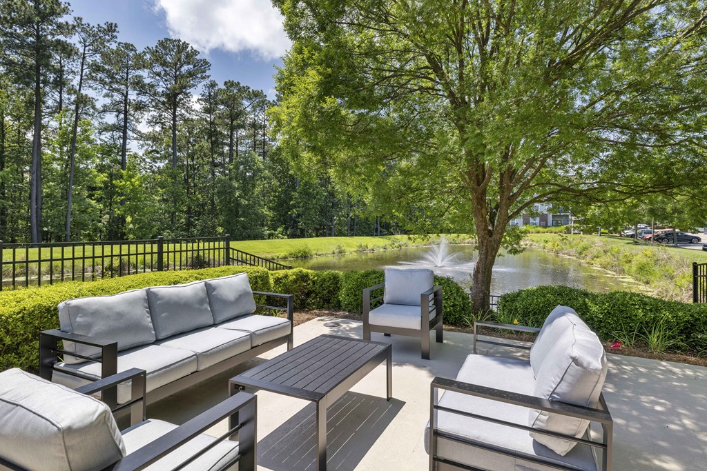 A patio with a table and chairs overlooking a pond.