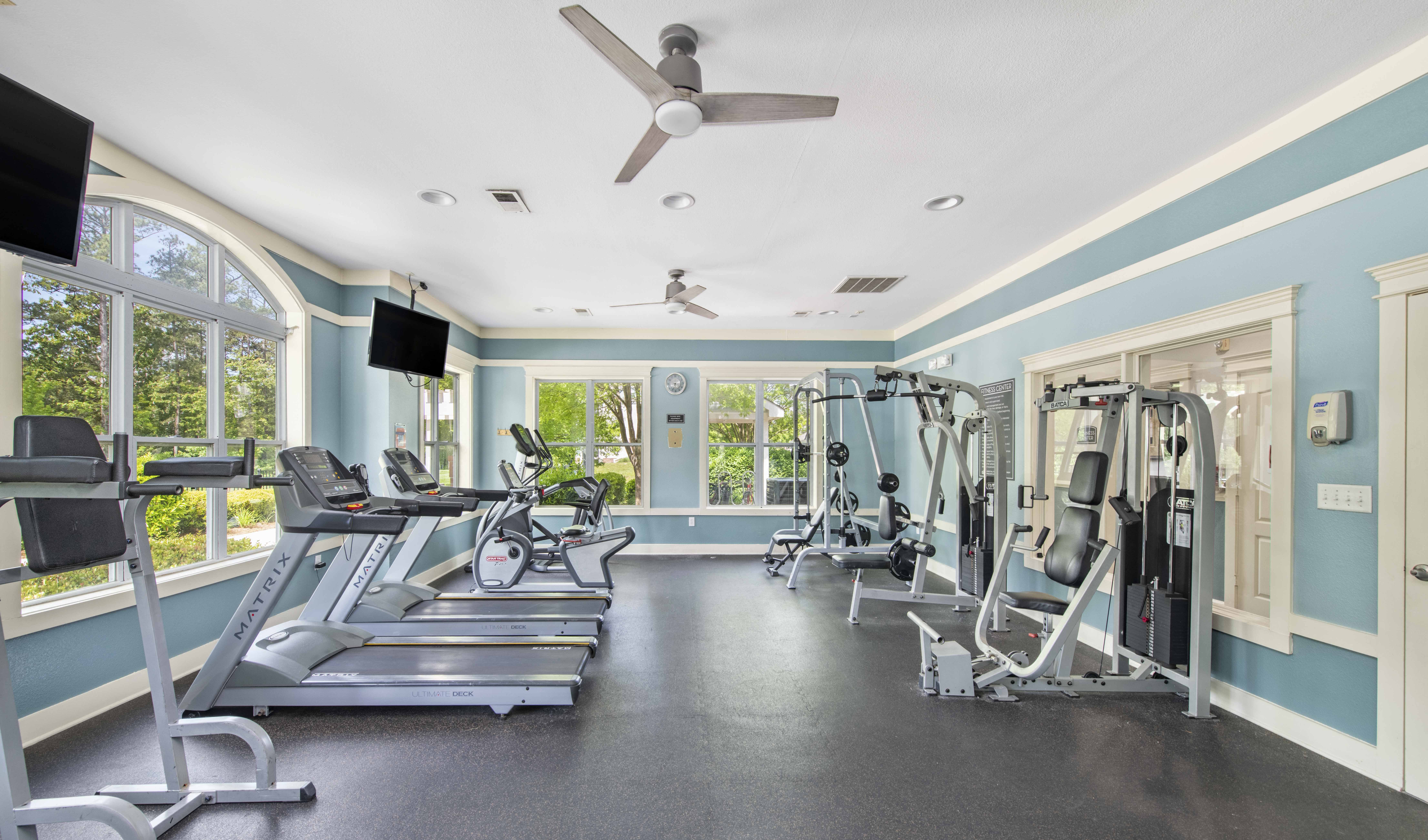 the gym has plenty of exercise equipment and windows