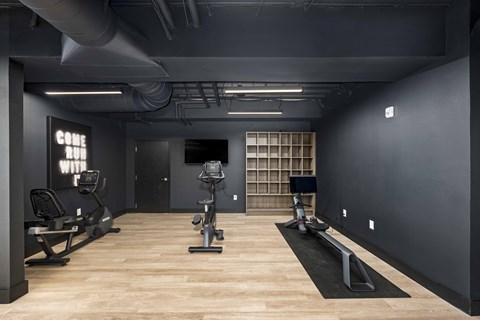 A gym with treadmills, elliptical machines, and a bench.