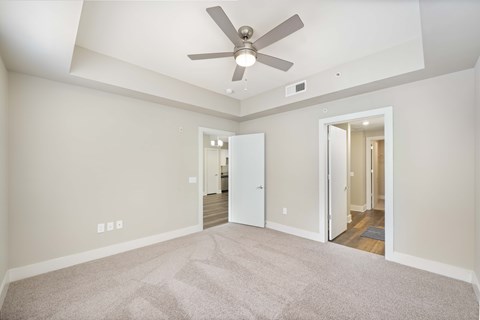 A room with a ceiling fan and carpeted floor.