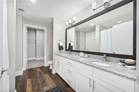 A bathroom with a wooden floor and white cabinets.