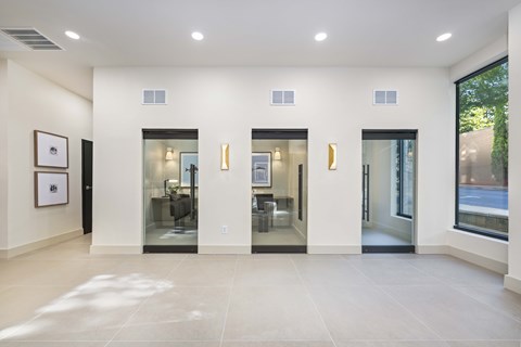 A white hallway with three glass doors.