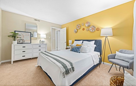 a bedroom with yellow walls and a white bed