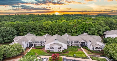 an aerial view of a house with trees and a sunset behind it