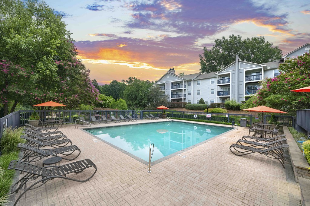 a pool with chairs and umbrellas next to a building