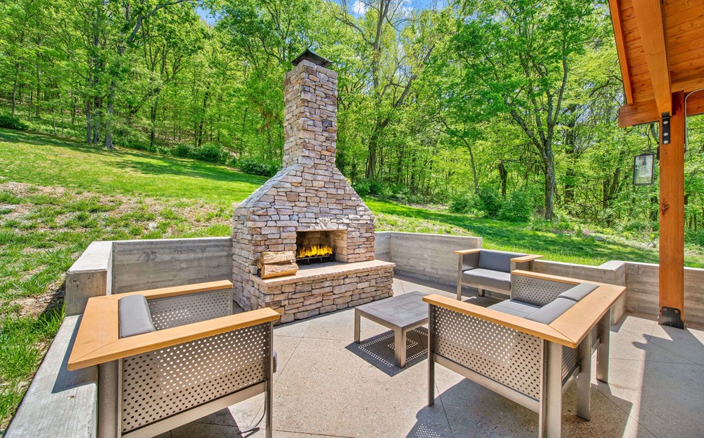 a backyard patio with a stone fireplace and tables