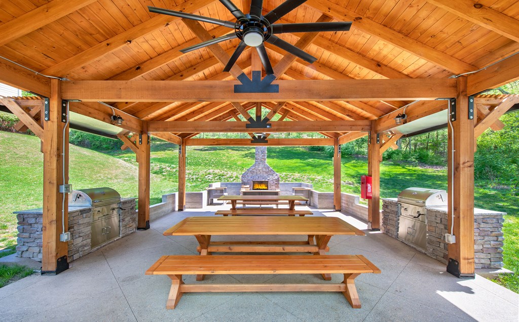 a covered patio with picnic tables and a grill