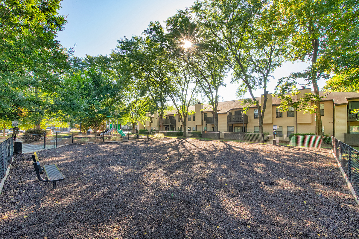 a dog park with trees and buildings in the background