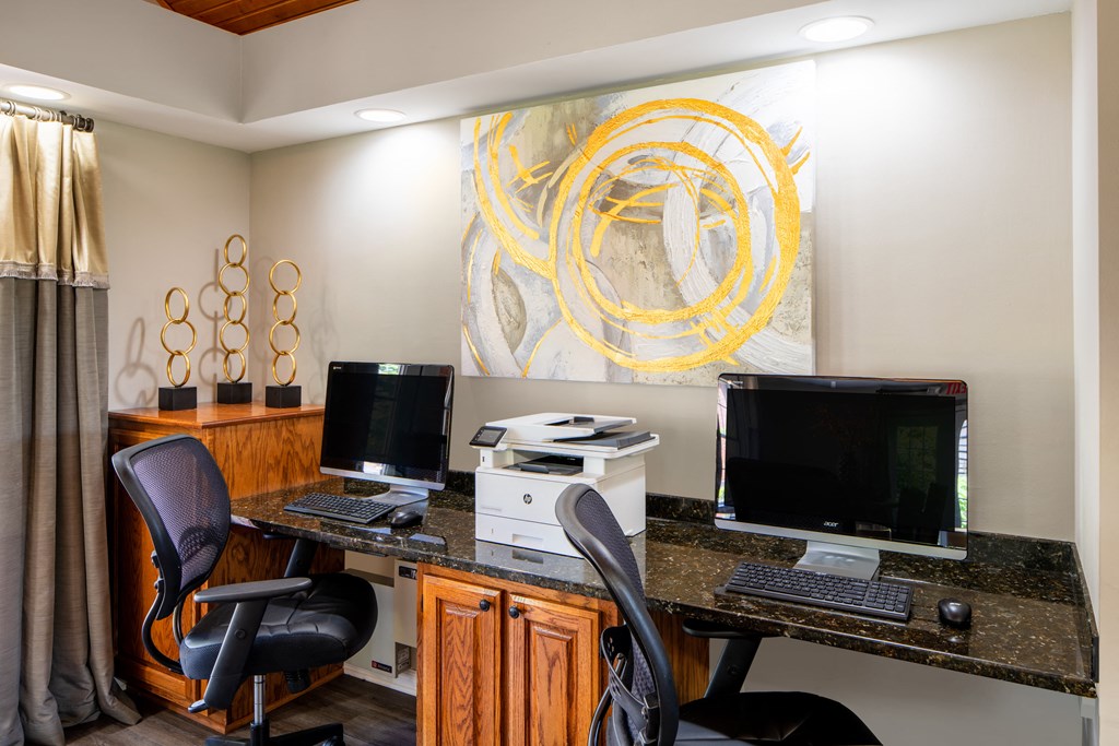 a home office with two computers and a painting on the wall