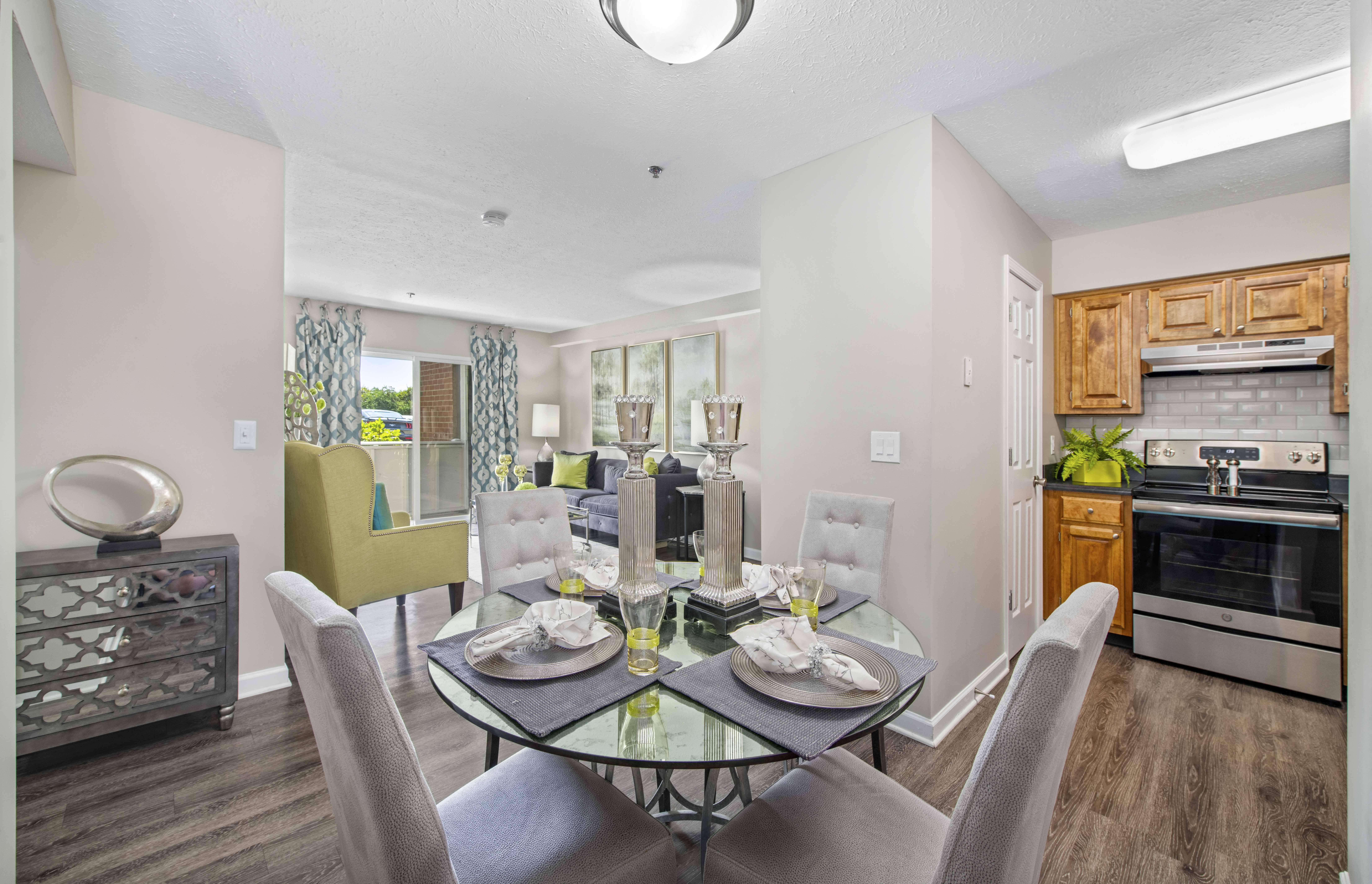 a dining room with a glass table and chairs and a living room with an oven