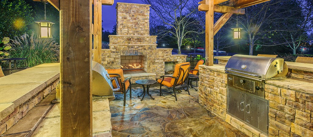 a backyard with a barbecue grill and a stone fireplace