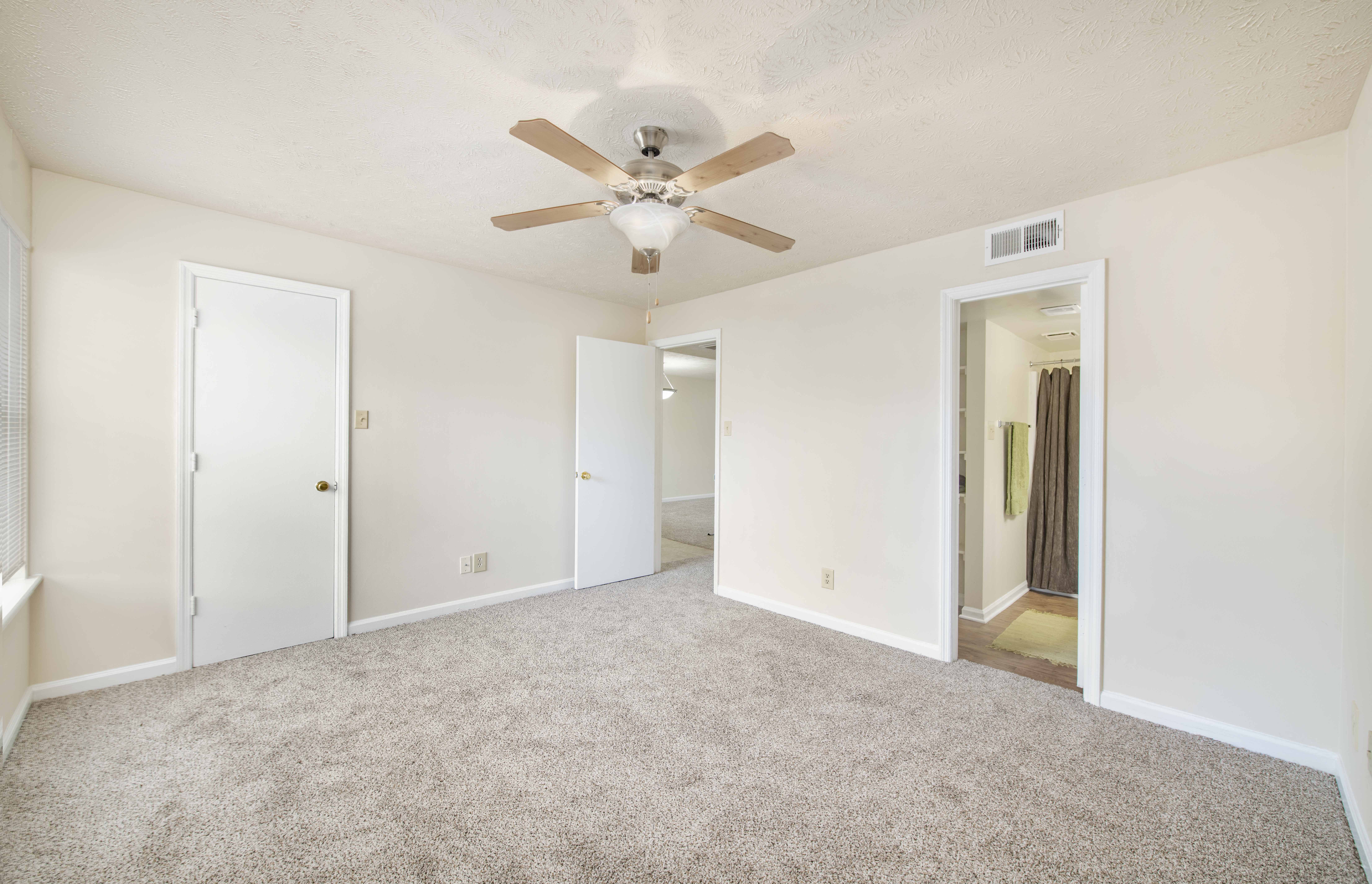 an empty living room with a ceiling fan