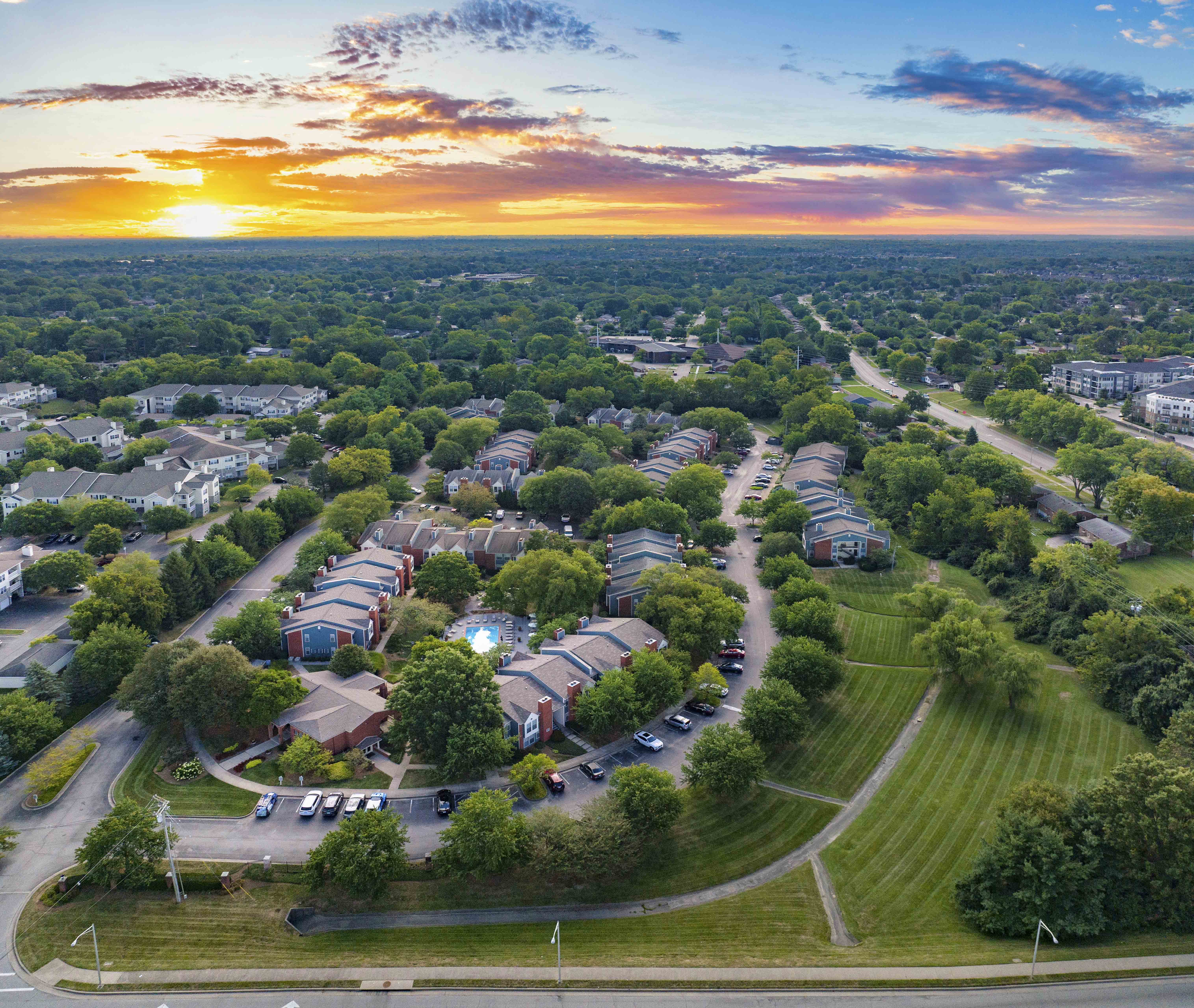 an aerial view of a neighborhood with houses and trees and a sunset