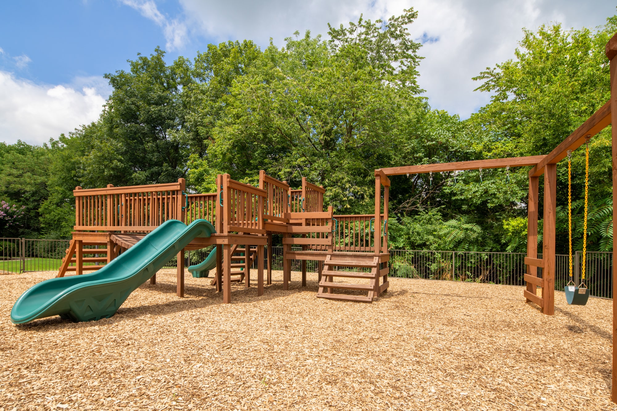 a playground with a slide and chairs in a backyard