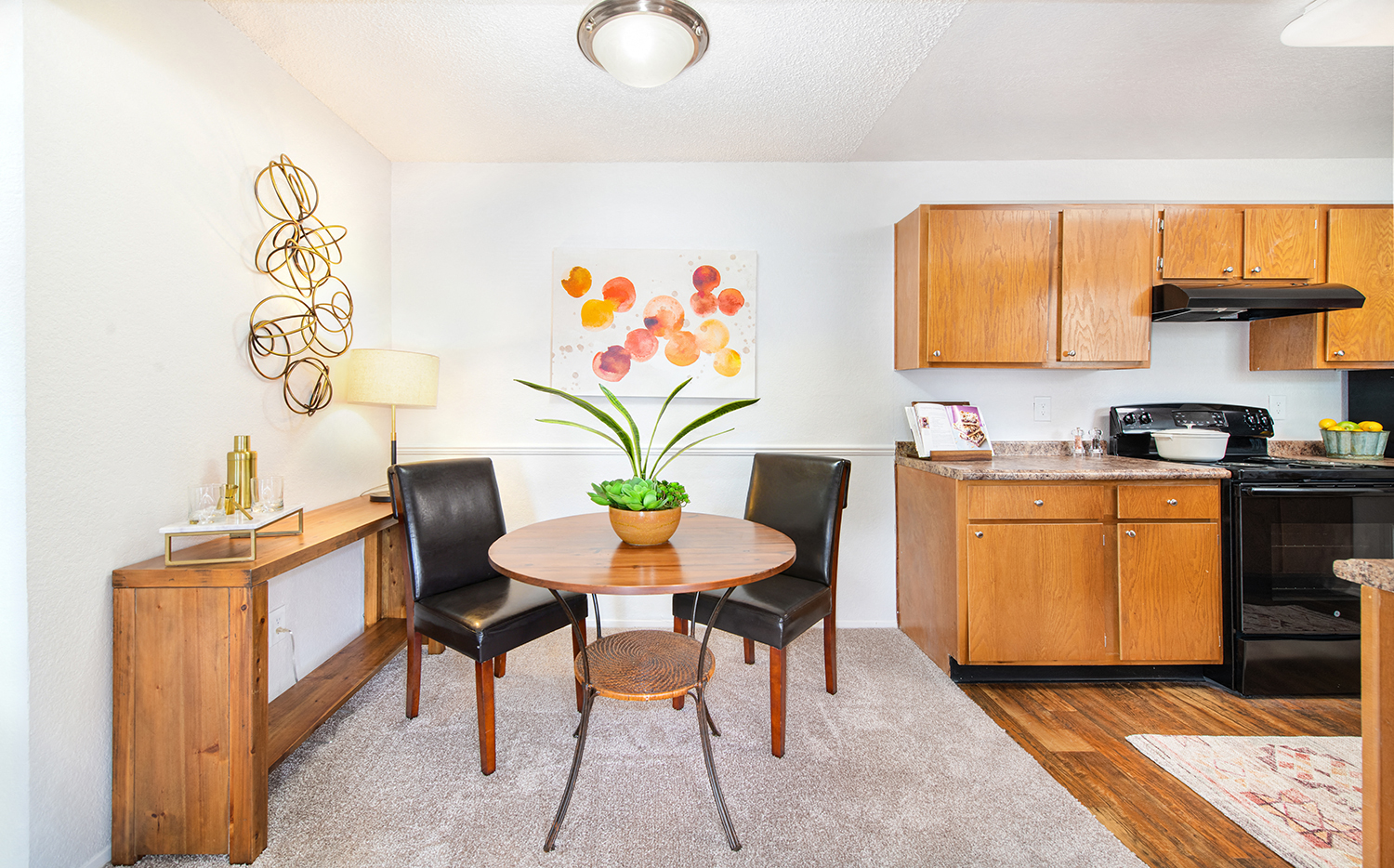 a dining room with a table and chairs and a kitchen with wooden cabinets
