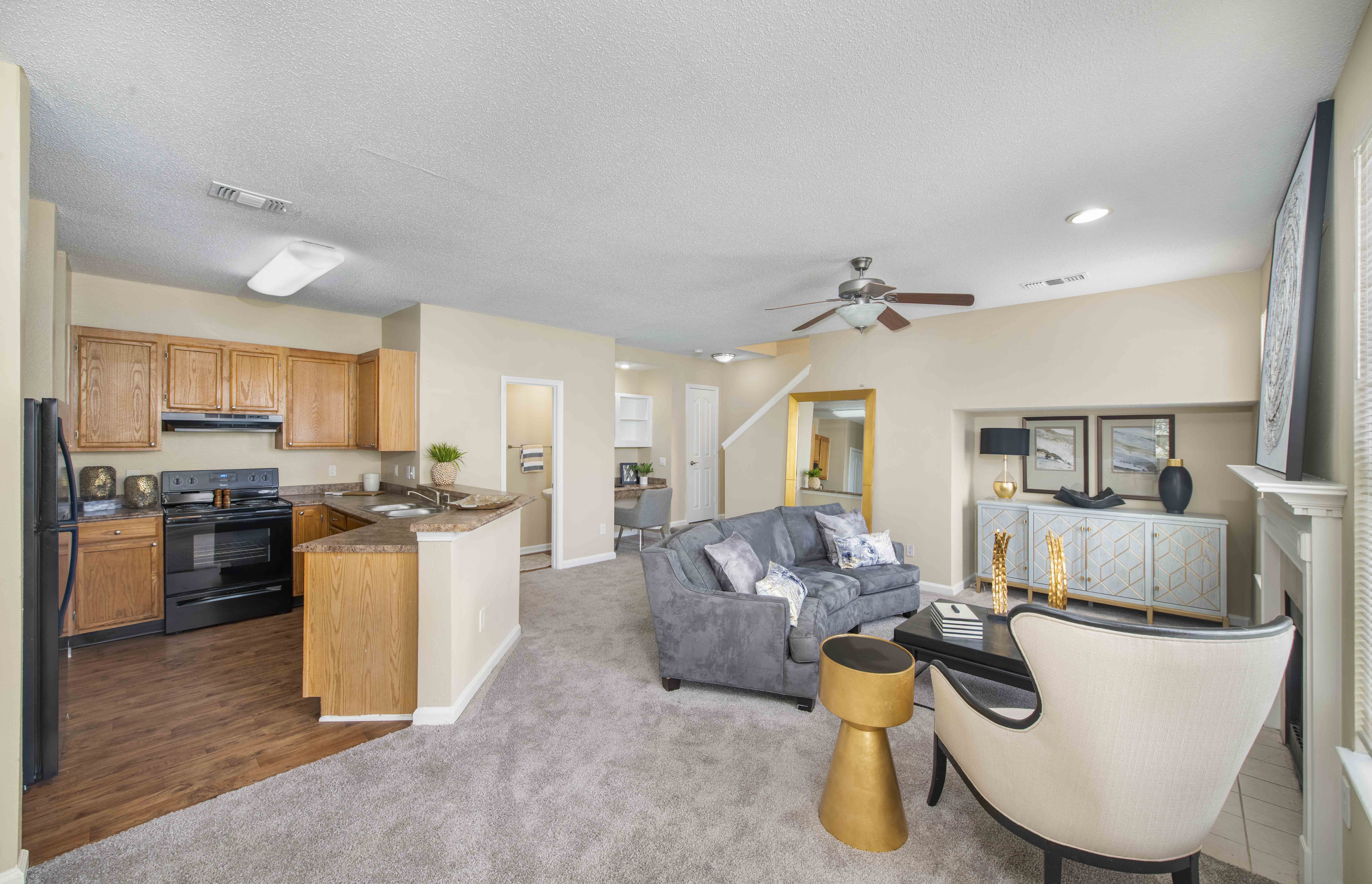 a living room and kitchen with a couch and a ceiling fan