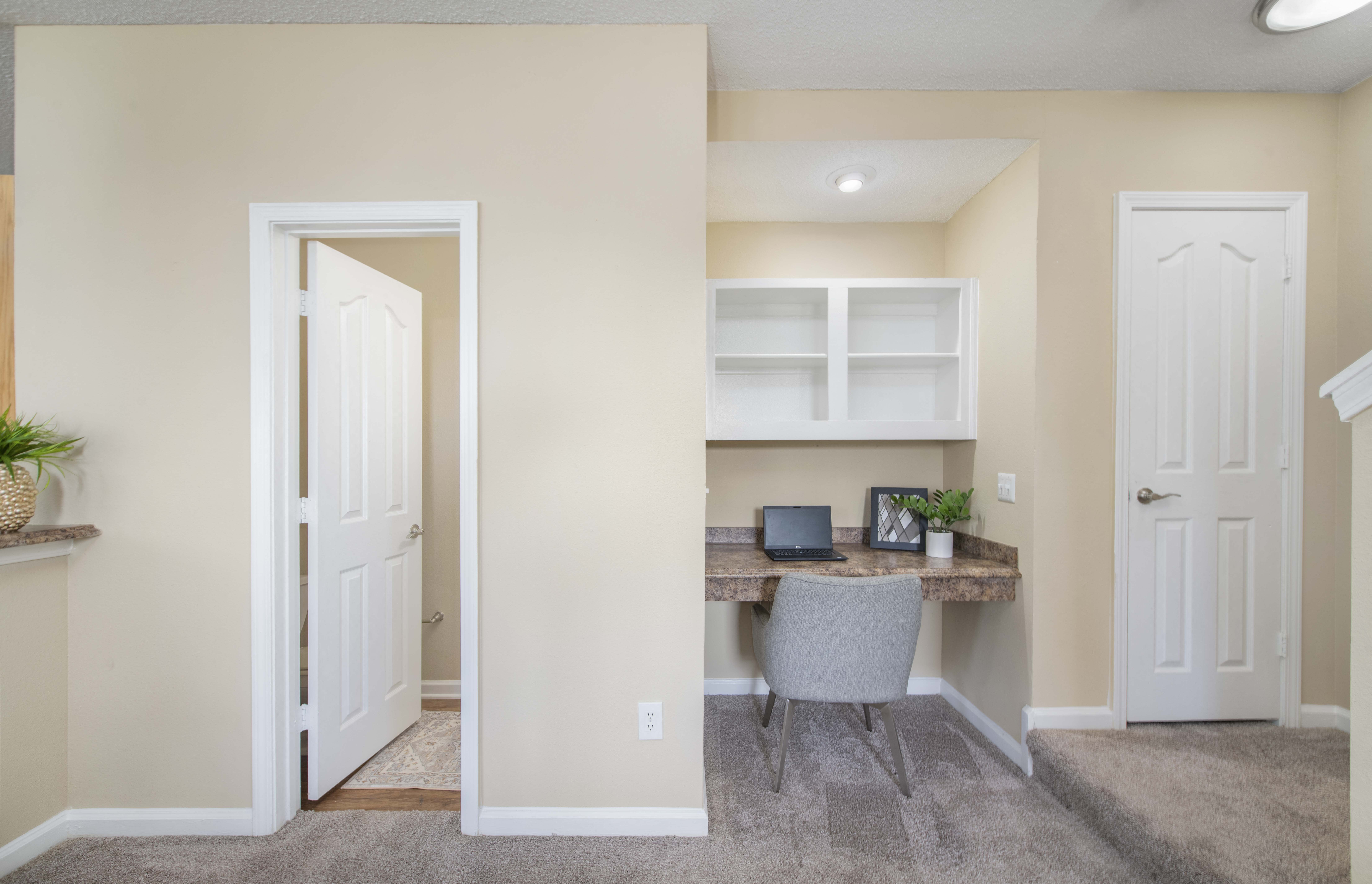 a home office with a desk and a door to a closet