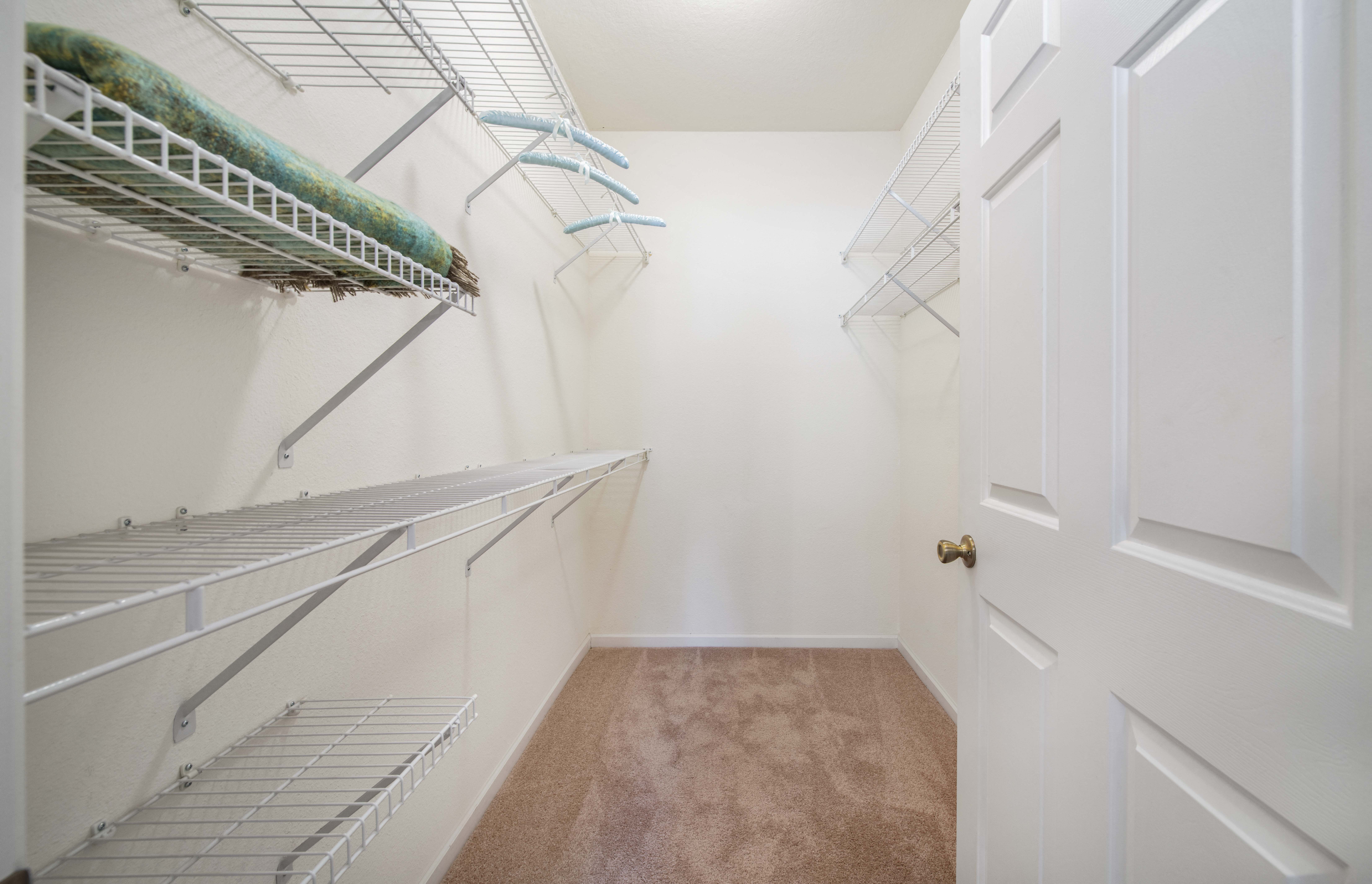 a walk in closet with white walls and shelves and a white door