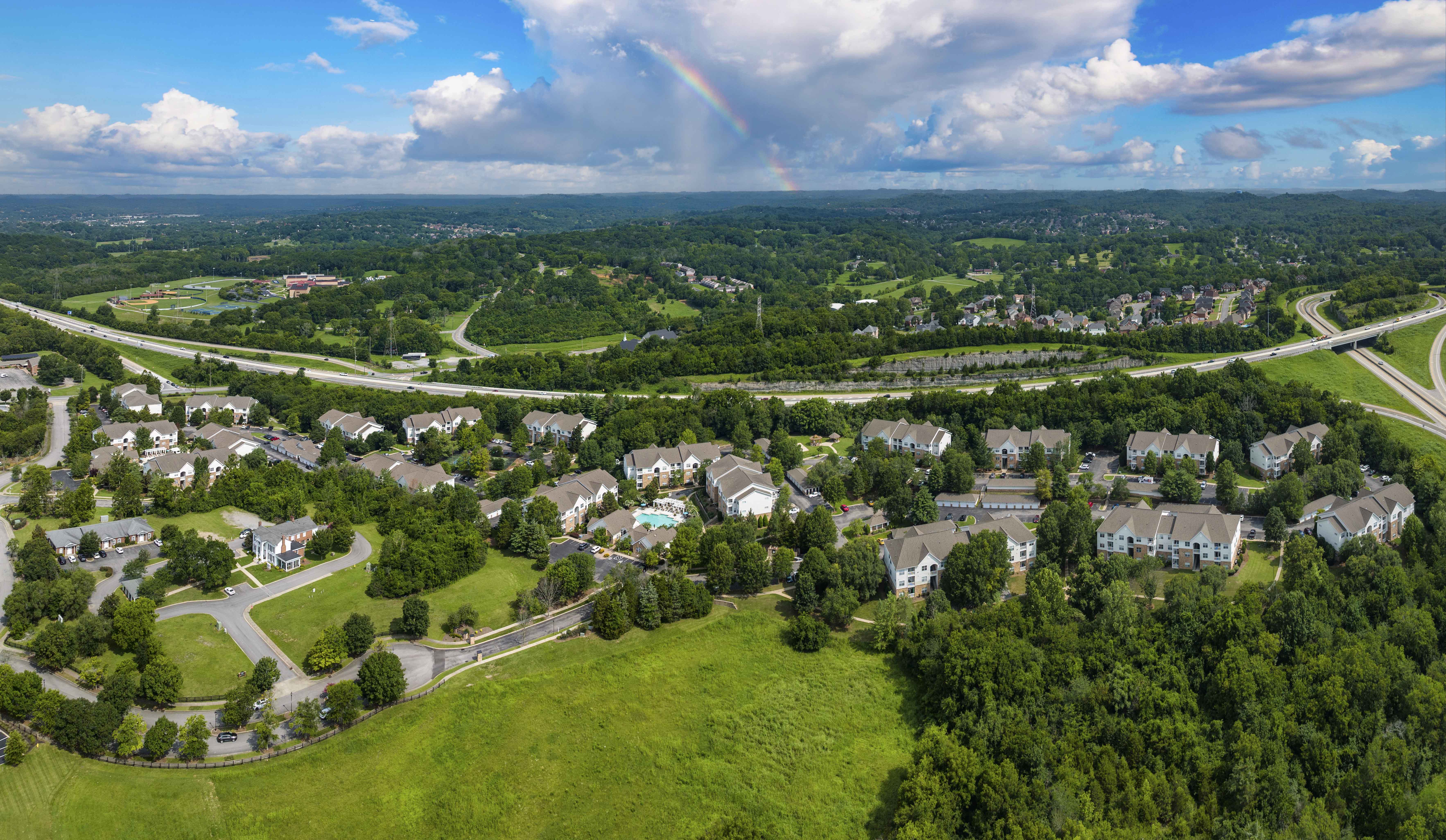 an aerial view of a neighborhood with a rainbow in the sky