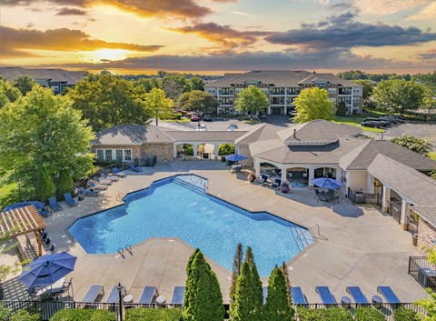 an aerial view of a swimming pool with umbrellas at sunset