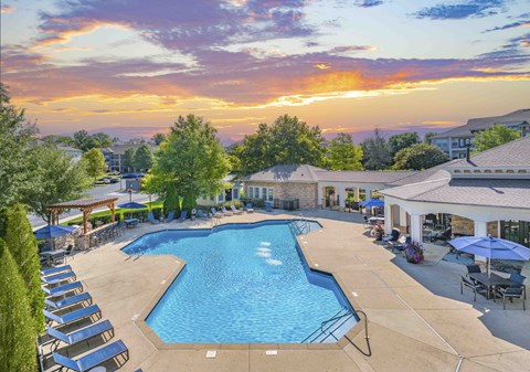 an aerial view of a swimming pool with a sunset in the background