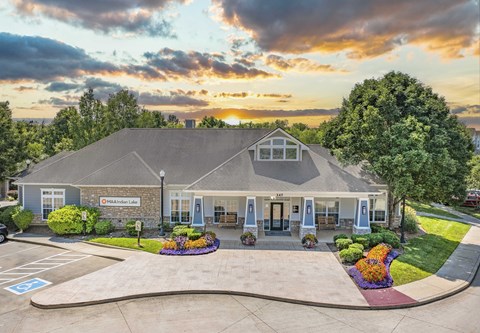 the front of a house with the sun setting behind it