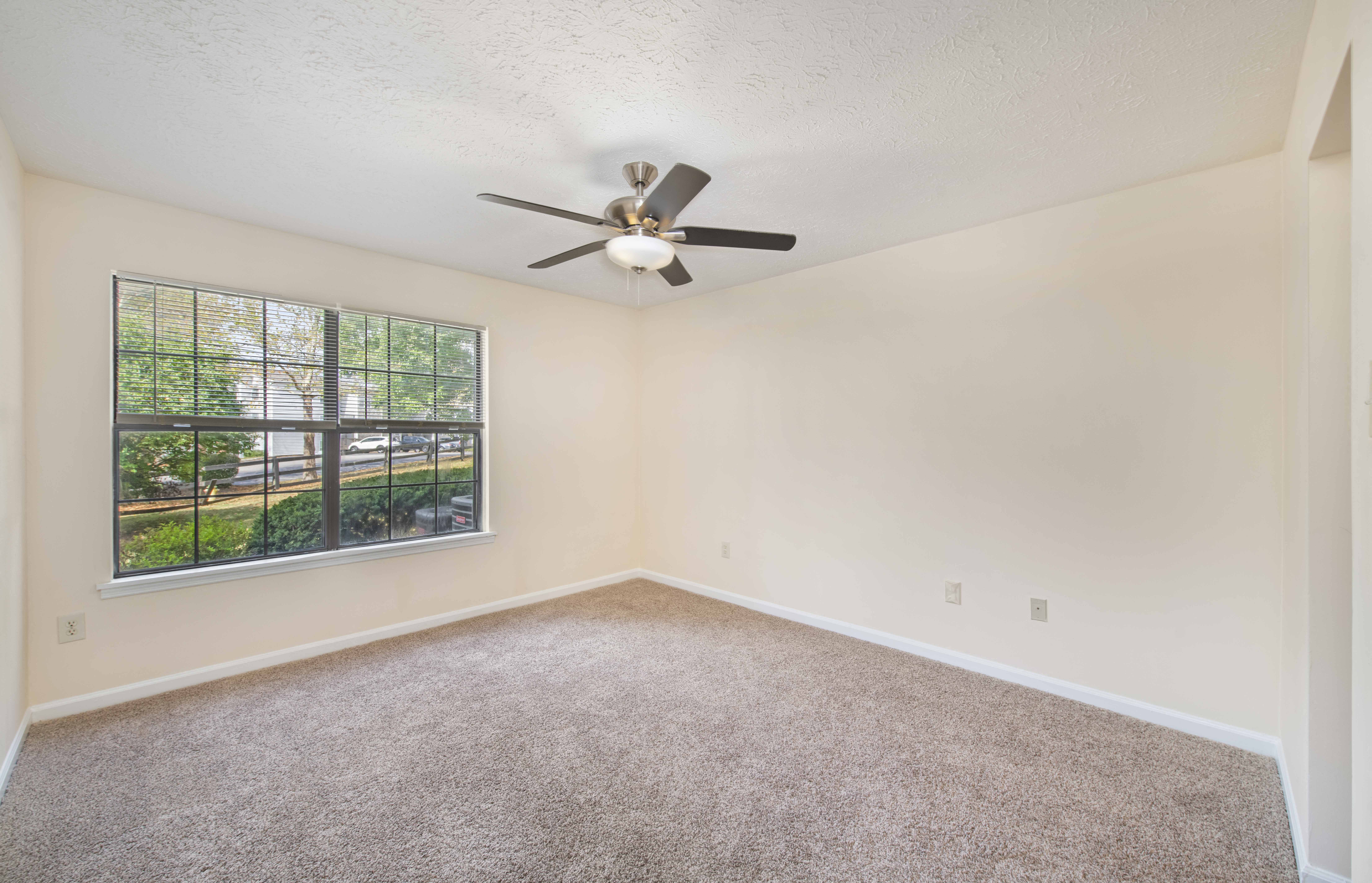 an empty living room with a ceiling fan and a window