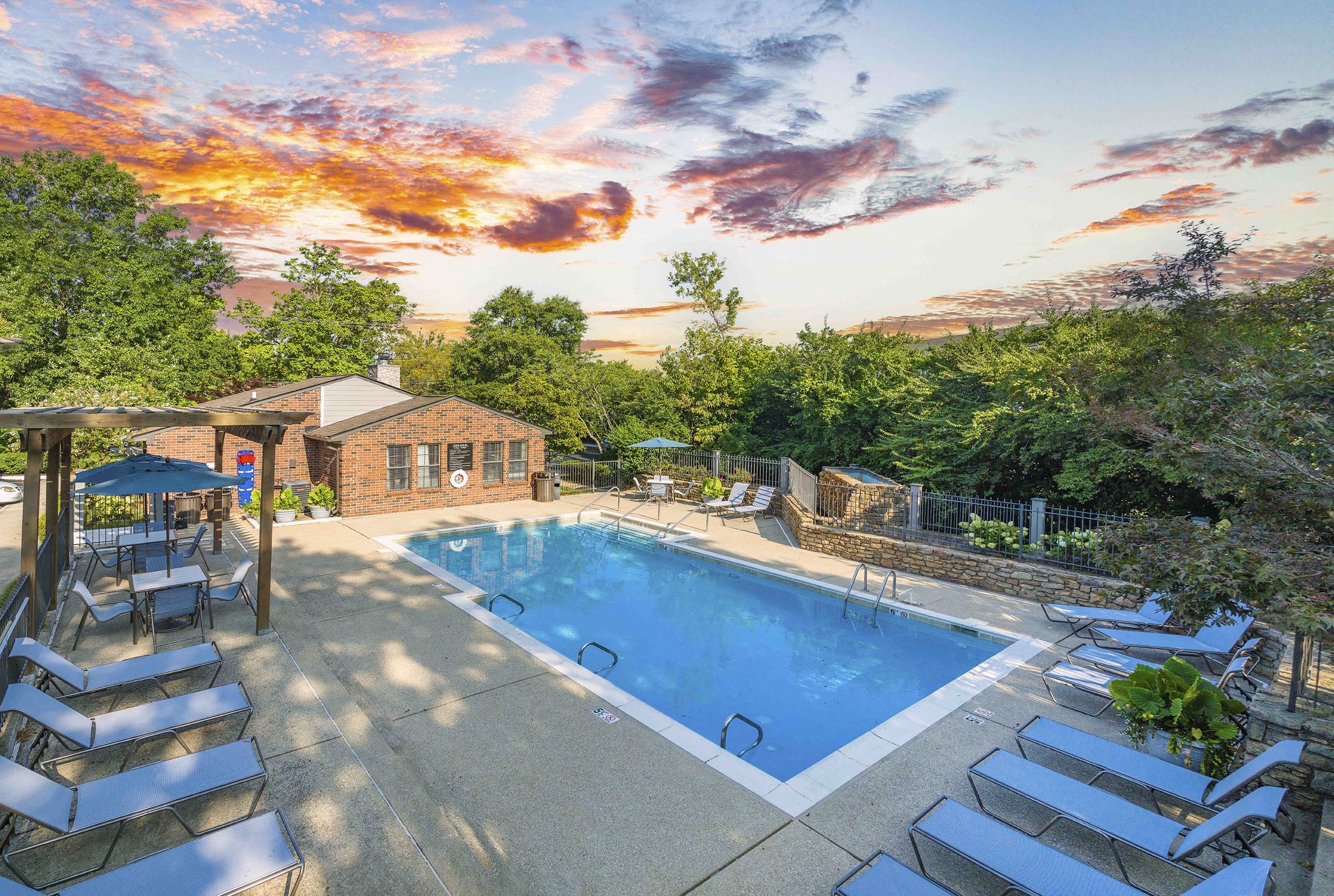 a pool with a house and a sunset in the background