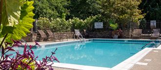 a swimming pool with chairs around it in front of a fence