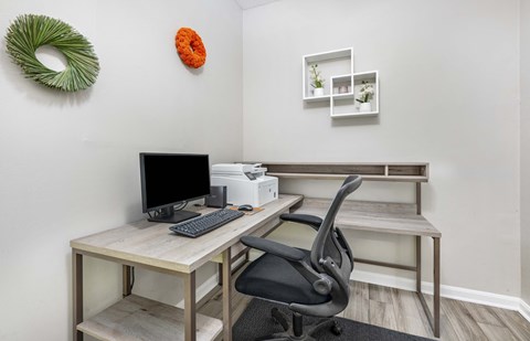 a desk with a computer and a chair in a room