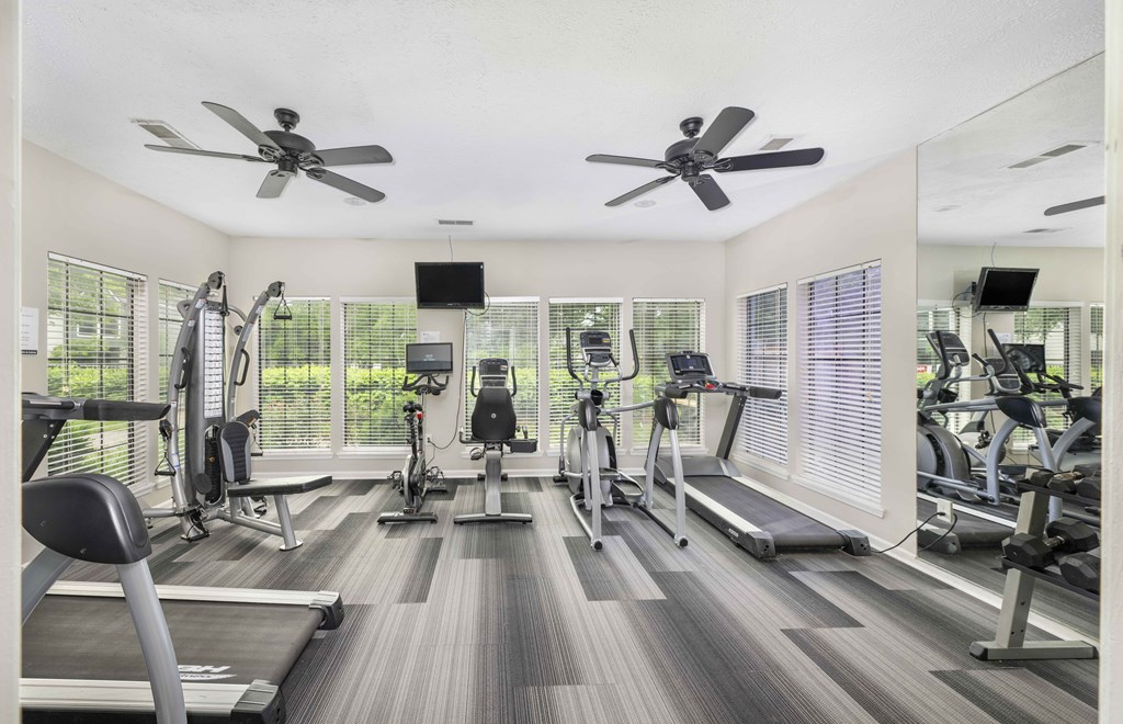 a gym with cardio machines and ceiling fans