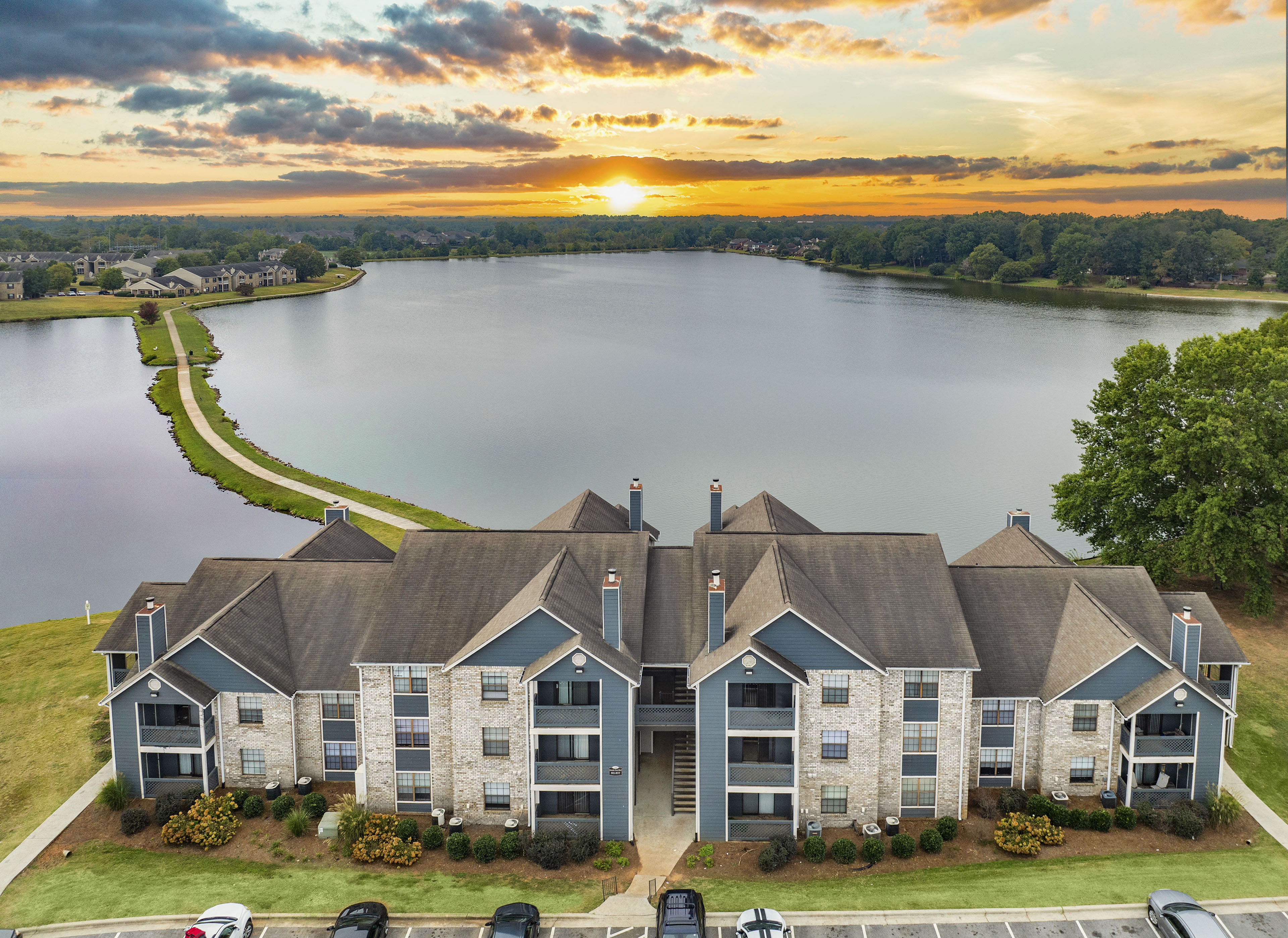 an aerial view of a house overlooking a lake at sunset