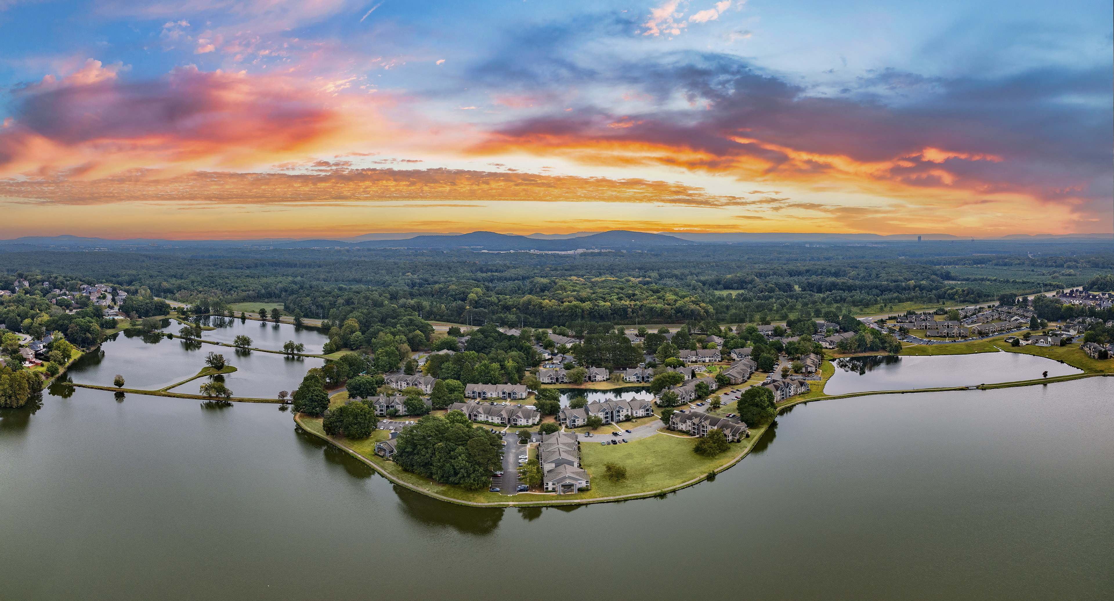 an aerial view of a subdivision with a body of water at sunset